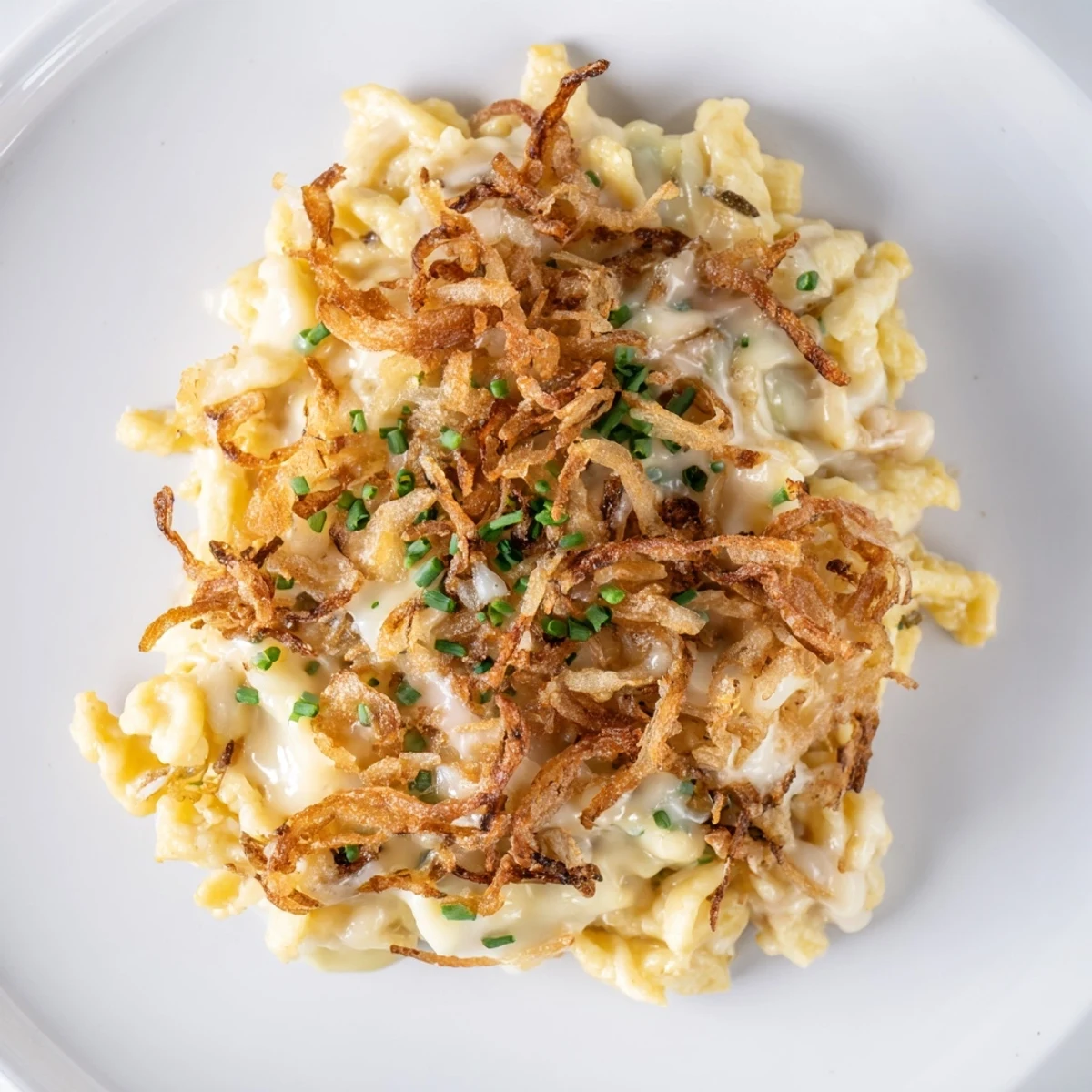 Herzhafte Baked Cheesy Spaetzle Pasta, überzogen mit knusprigen Zwiebeln und frisch garniert.